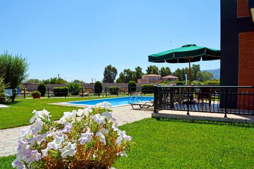 a pool with a table and an umbrella and flowers at Kalloni Beach Villas in Skala Kallonis