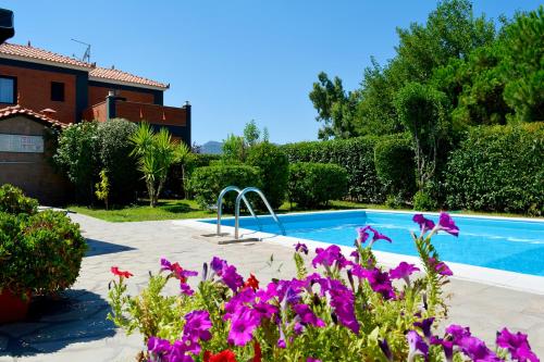 a swimming pool in front of a house with purple flowers at Kalloni Beach Villas in Skala Kallonis