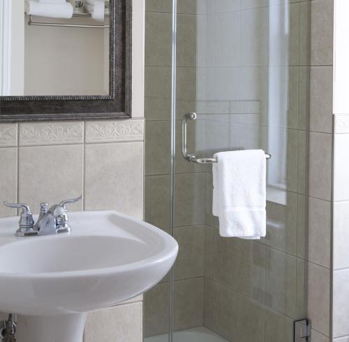 a bathroom with a sink and a shower with a mirror at Auberge du Trésor in Quebec City
