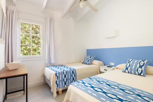 a bedroom with two beds and a window at Casa Blanca - villa con piscina a 30m del mar-Binibeca in Sant Lluis