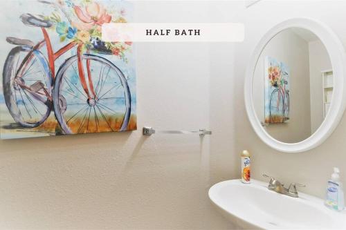 a bathroom with a sink and a painting of a bike at Katy, GRAND TEXAS SIZE HOUSE, 6 Bedrooms 14 Beds - Sedgecreek in Katy