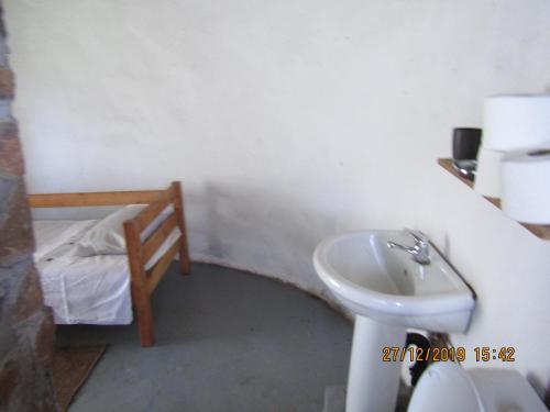 a small bathroom with a sink and a bed at Libibing chalets in Mokhotlong