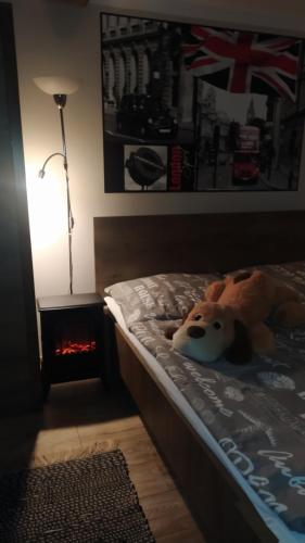 a teddy bear laying on a bed next to a lamp at Ubytovanie na sukromí in Banská Štiavnica