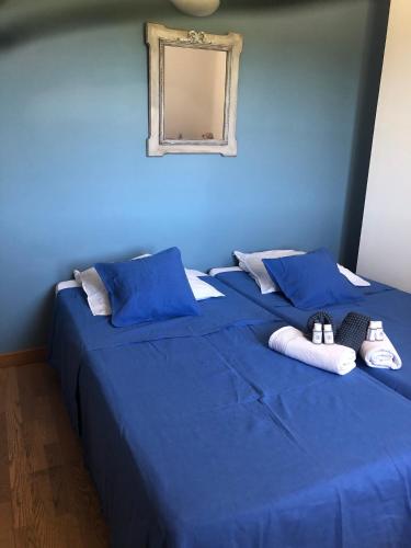 - un lit bleu avec 2 paires de chaussons et un miroir dans l'établissement Mas en Luberon GORDES, à Gordes