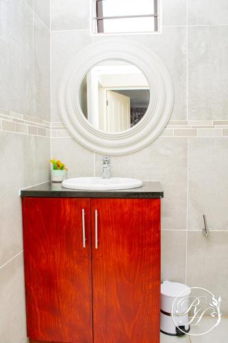 a bathroom with a red wooden cabinet with a mirror at Roseland House Self Catering in Durban