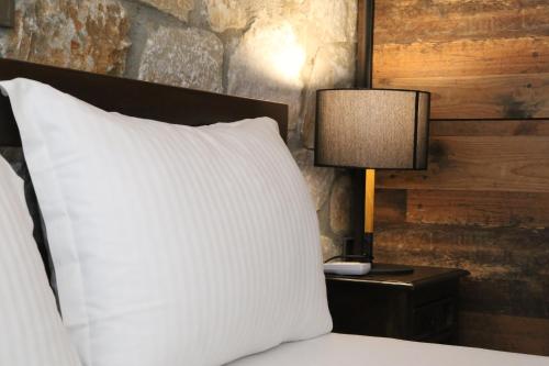 a bed with a white pillow and a lamp on a table at Petrines Villes Avramilias in Avramiliá