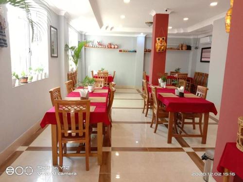 a restaurant with red tables and chairs in a room at The Pegu Lodge in Bago