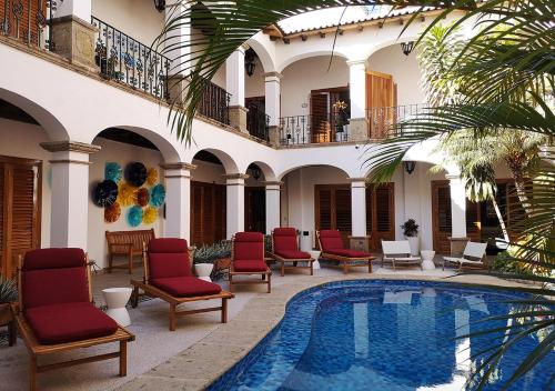 a courtyard with a pool and chairs and a building at Casa Carmen in Puerto Vallarta