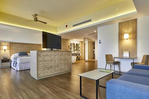 a hotel room with a bed and a living room at Riu Palace Baja California - Adults Only - All Inclusive in Cabo San Lucas