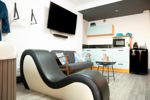 un soggiorno con divano e TV a parete di Le Charm'Sablais a Les Sables-dʼOlonne