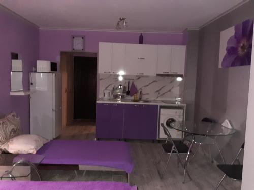 a kitchen with purple walls and a table and a refrigerator at Parus 4 Studio in Pomorie