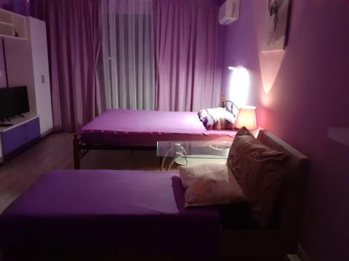 a purple room with two beds and a table at Parus 4 Studio in Pomorie