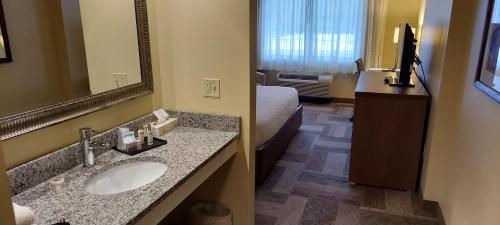 a bathroom with a sink and a bed and a mirror at Belfast Harbor Inn in Belfast