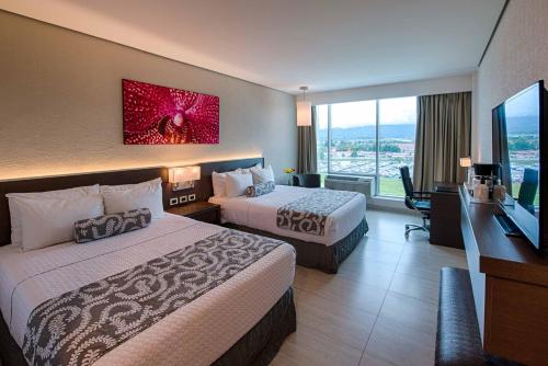 a hotel room with two beds and a flat screen tv at Crowne Plaza Airport by IHG in Tocumen