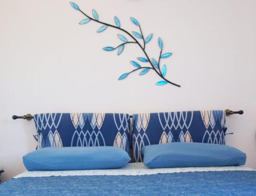 uma cama com almofadas azuis e um ramo na parede em B&B Nel Giardino In Fiore em Castiadas