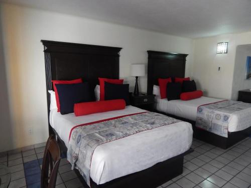 two beds in a hotel room with red and blue pillows at Studio At Marina Los Cabos in Cabo San Lucas