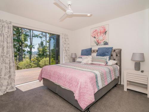 - une chambre avec un lit et une grande fenêtre dans l'établissement Treetop Bach - Whangamata Holiday Home, à Whangamata