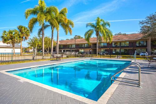 a swimming pool in front of a building with palm trees at Americas Best Value Inn & Suites Melbourne in Melbourne