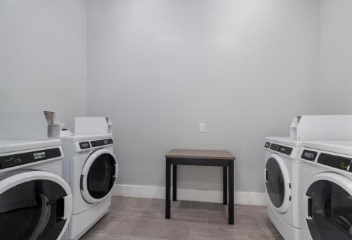 a laundry room with two washing machines and a stool at Studio 6 Katy, Tx in Katy