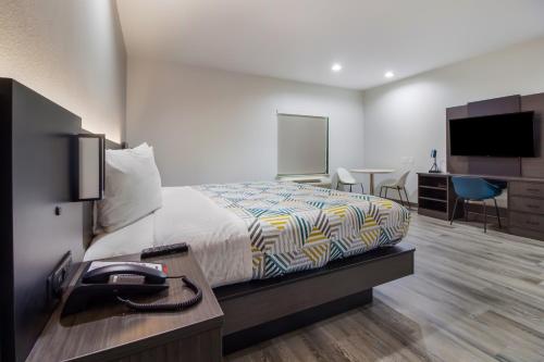 a hotel room with a bed and a desk with a phone at Studio 6 Katy, Tx in Katy