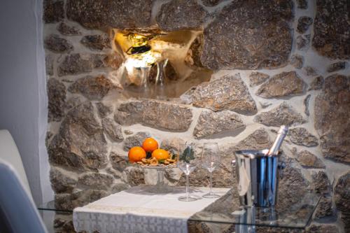 a table with a bowl of oranges and wine glasses at Apartments Mikulin Family in Punat
