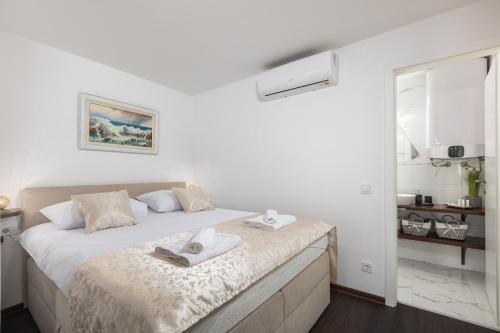 a white bedroom with a bed with towels on it at Apartments Mikulin Family in Punat