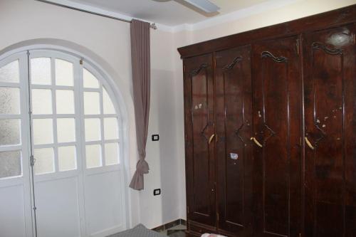 Habitación con un gran armario de madera y una ventana. en Al Ramla Guest House, en Luxor