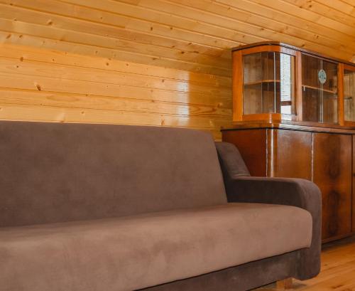 a couch in a room with a wooden wall at Садиба У Романа 'двохрівневий номер' in Verkhneye Sinevidnoye
