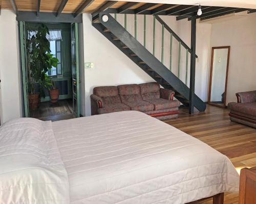 a bedroom with a bed and a couch and a staircase at Hostal Latina in Cuenca