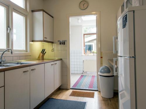 een keuken met een wastafel en een deur naar een badkamer bij Egmond-vakantiewoningen in Egmond aan Zee