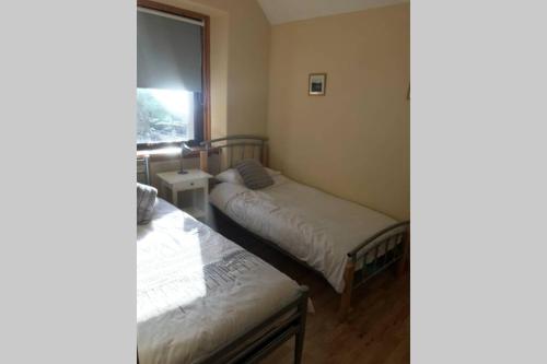 two beds in a small room with a window at Mallaig Self Catering Apartment in Mallaig