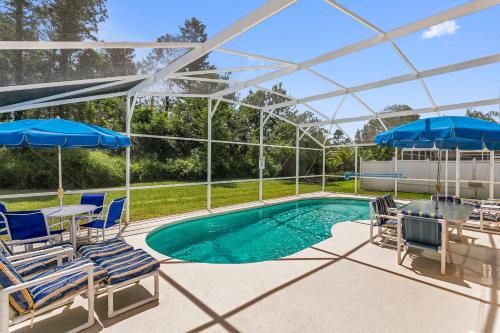 a swimming pool with chairs and umbrellas at South Facing Pool Deck - Private Outlook - Game Room - Family Friendly - Nr Disney in Orlando