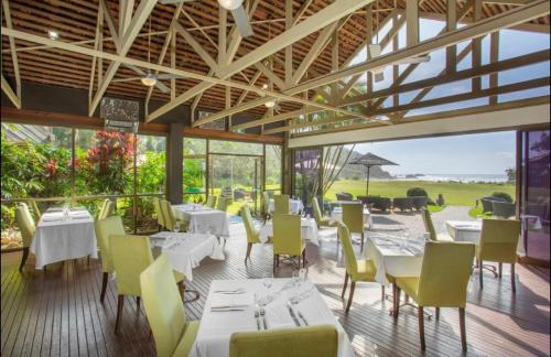 a restaurant with white tables and yellow chairs at Superb Villa in Beach Resort in Coffs Harbour