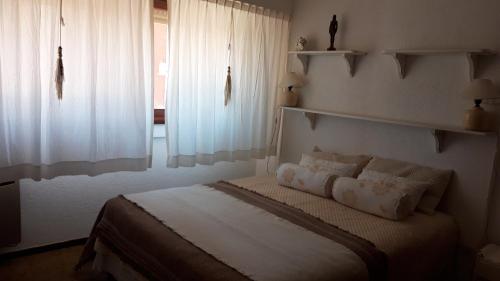 um quarto com uma cama com cortinas brancas e uma janela em Depto, centro, 3 de la playa, luminoso con balcón em Pinamar