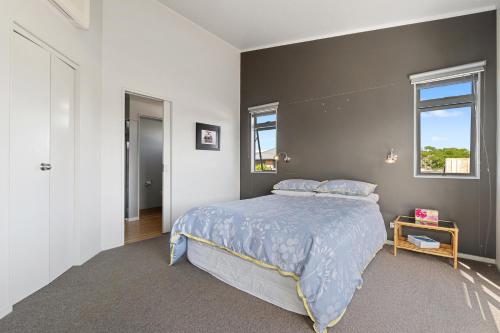 a bedroom with a bed with a blue comforter at Restful Ruakaka - Ruakaka Holiday Home in Ruakaka