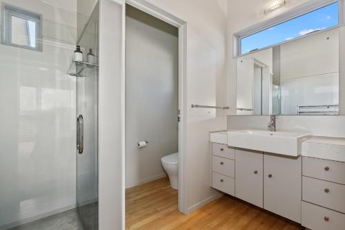 a white bathroom with a sink and a shower at Restful Ruakaka - Ruakaka Holiday Home in Ruakaka