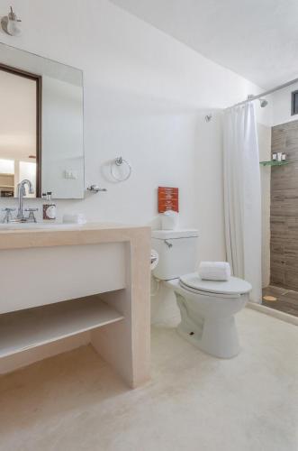 un bagno con un water, un lavandino e uno specchio di Kin Ha Tulum Hotel a Tulum