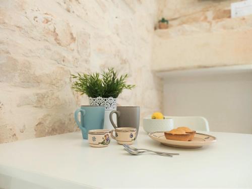 a table with cups and a plate of food on it at La Vernèa in Ceglie Messapica