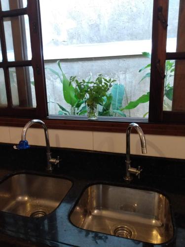 a kitchen sink with two faucets in front of a window at Hospedaria Namastê in Peruíbe