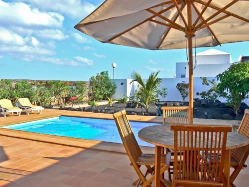 un patio con mesa, sillas y piscina en Belvilla by OYO Mango 4 pax, en Playa Blanca