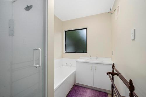 a white bathroom with a sink and a bath tub at Wharerata - Otaki Beach Holiday Home in Otaki Beach