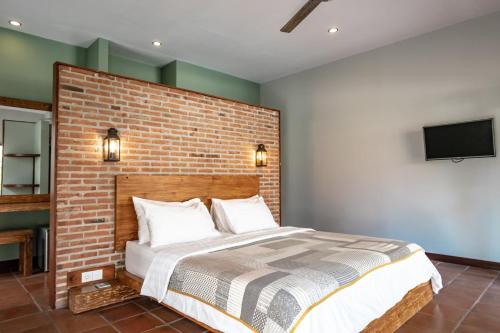 Belukar Villas في غيلي تراوانغان: غرفة نوم بحائط من الطوب وسرير