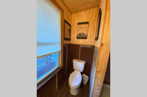 a small bathroom with a toilet and a window at The Cowboy Cabin in Marble Falls