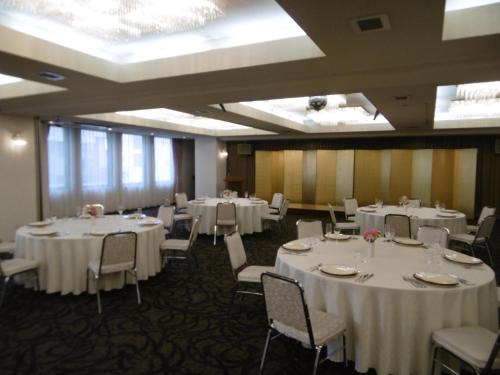 uma sala de banquetes com mesas e cadeiras brancas em アーバンホテル二本松 em Nihommatsu