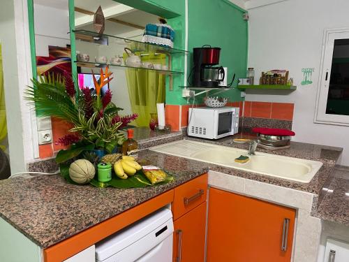 a kitchen with a sink and a counter with fruit on it at Sunrise in Le Moule