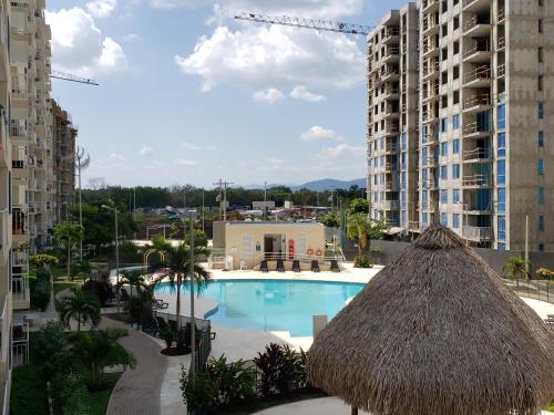 a swimming pool with a straw umbrella and some buildings at Piscina & Descanso - Puerto Azul- con todas las comodidades! in Ricaurte