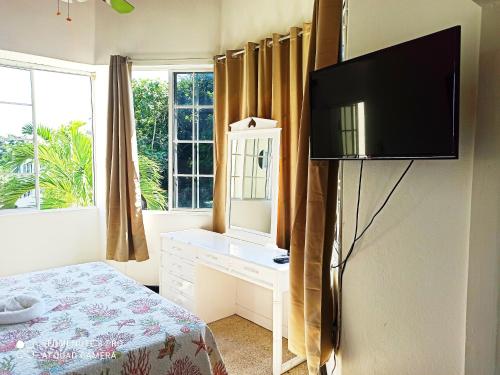 a bedroom with a bed and a television on a wall at Columbus Heights Apt 26 F in Ocho Rios