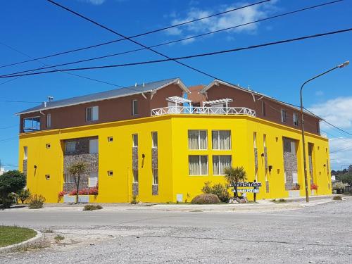 un edificio amarillo al lado de una calle en Complejo Bahia Ballenas en Rawson