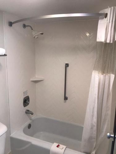 a bathroom with a tub and a shower curtain at Ramada by Wyndham Ligonier in Ligonier