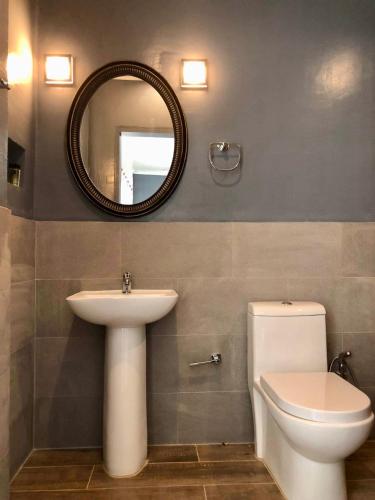 a bathroom with a sink and a toilet and a mirror at PAYAG SUITES in General Luna